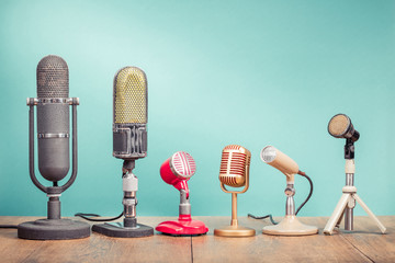 Wall Mural - Retro old microphones for press conference or interview recording on table front gradient aquamarine background. Vintage old style filtered photo