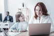 © zinkevych - Pleasant day. Joyful mature woman smiling while working on a laptop and listening to the questions of her curious little daughter.