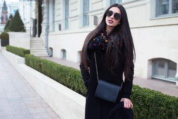 Wall Mural - Outdoor portrait of young beautiful fashionable woman with long hair posing in casual outfit with small black bag. Model looking at camera,Female fashion, beauty concept.