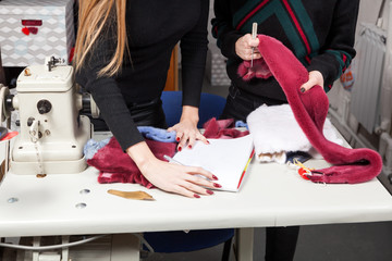 Clode up of a two young women furriers are discussing how to properly cut natural fur to make a woman's fur coat. The process of making a woman's fur coat