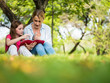 © ronnarong - Mother and daughter reading a book together in a park. Family, lifestyle and education concept