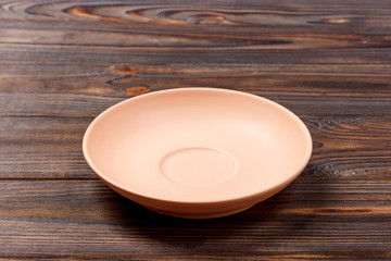 empty orange matte plate on wooden background. Perspective view