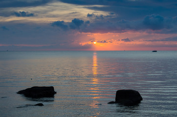 Sunset by the sea with two rocks in front.