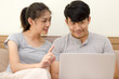 © Pormezz - Young happy asian couple searching hotel for holiday trip via laptop computer at home.