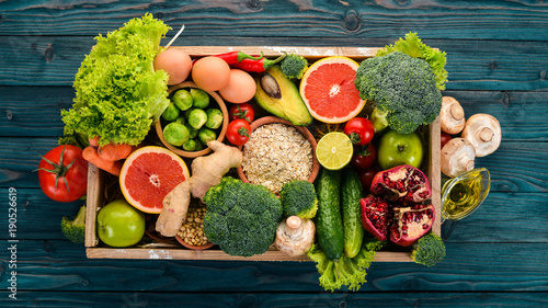 The concept of healthy food. Fresh vegetables, nuts and fruits in a wooden box. On a wooden background. Top view. Copy space. © Yaruniv-Studio