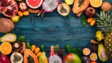 Tropical Fruits, Papaya, Dragon Fruit, Rambutan, Tamarind, Cactus Fruit, Avocado, Granadilla, Carambola, Kumquat, Mango, Mangosteen, Passionfruit, Coconut. On A Wooden Background.