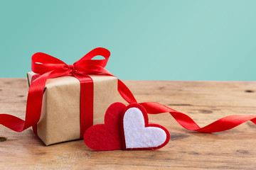 Valentine Gift Box with red hearts on rustic wooden table against green pastel with copy space. Happy Valentine Day or greeting card design concept.