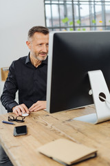 Wall Mural - Businessman working at a large computer monitor