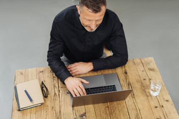 Wall Mural - High-angle view of a man using a laptop at desk