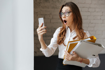 Canvas Print - Shocked business woman indoors using mobile phone