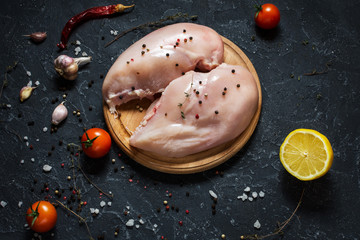 Fresh raw chicken fillet, spices and herbs on black stone background