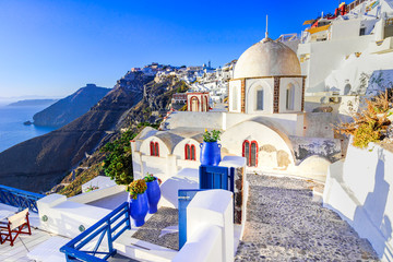 Fira, Santorini - Greek Islands landmark with white village, cobbled paths, greek orthodox blue church and sunset over caldera. Cyclades, Greece