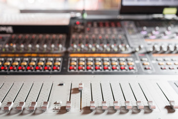 od adjusters and red buttons of a mixing console. It is used for audio signals modifications to achieve the desired output. Applied in recording studios, broadcasting, television.