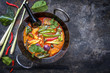 Traditional Thai kaeng phet red curry with vegetables as top view in a wok with copy space right