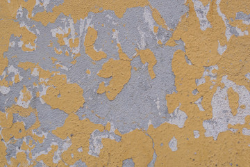 Isolated, close-up shot of yellow, grey and white chipping paint, on a stucco wall