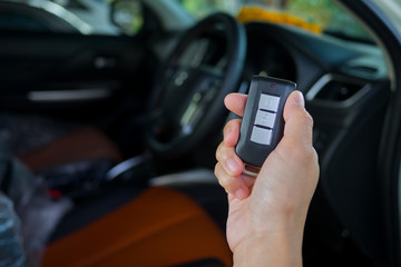 press buttom to unlock door . selective focus of Hand presses on the remote control car. car remote on hand with car background. remote control car 