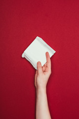 Wall Mural - partial view of woman holding menstrual pad in hand isolated on red