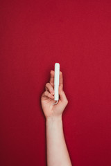 Wall Mural - cropped shot of woman holding tampon in hand isolated on red