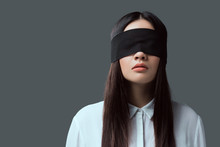Young Woman Wearing Black Blindfold Isolated On Grey