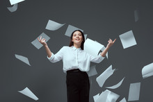 Smiling Young Businesswoman Throwing Papers Isolated On Grey