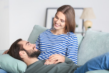 Poster - Young couple resting on sofa after moving to new home