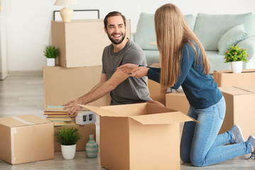 Poster - Young couple packing moving boxes in room