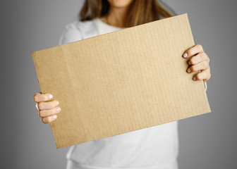 Wall Mural - A young girl in a white jacket holding a piece of cardboard. Prepared for your text