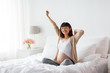 © Syda Productions - happy pregnant asian woman sitting in bed at home