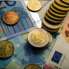 paper euro banknotes and coins. The coin is two euros. Currency of the European Union.