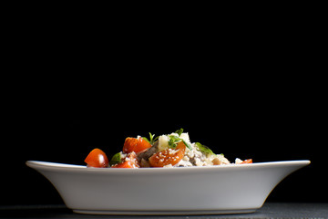 Italian pasta with cheese, cherry and basil on a black background