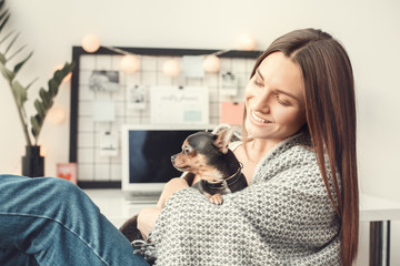 Young woman freelancer indoors home office concept winter atmosphere with puppy