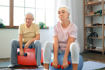 Wall Mural - Senior couple exercise together at home doing aerobics with dubbells down