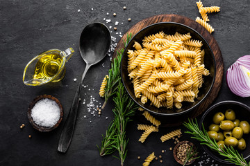 Wall Mural - Pasta and ingredients for cooking on black background, top view. Italian food