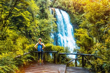 Poster - Woman hiker enjoys waterfall view from viewpoint surrounded by lush forest and vegetation. Chile