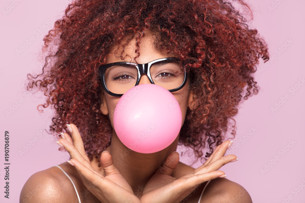 Afro girl blowing bubble gum balloon. - obrazy, fototapety, plakaty 