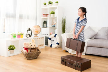 smiling female kid sailor carrying retro suitcase