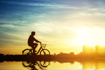 Wall Mural - Silhouette of bicyclist riding the bike on a rocky trail at seaside on colorful sunset sky background. Active outdoors lifestyle for healthy concep