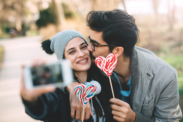 A happy guy and a girl hold a lollipop in their hands.