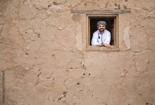 arab man in traditional omani outfit in an old castle, looking out of a window Tableau sur Toile