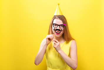 Wall Mural - Young woman holding paper party sticks on a solid background