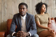 Frustrated upset african couple in quarrel sitting on sofa not talking after fight, stubborn disappointed black man ignoring sad depressed offended woman, problem in marriage relationships concept