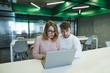 © bodnarphoto - Beautiful young couple working with a laptop in a stylish, modern office. A man and a girl are looking at the notebook monitor in the office.