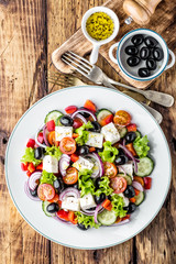 Wall Mural - Greek salad of fresh cucumber, tomato, sweet pepper, lettuce, red onion, feta cheese and olives with olive oil. Healthy vegetarian food