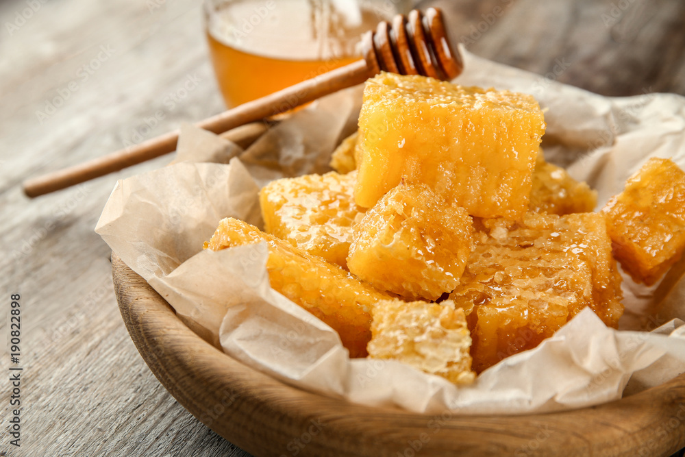 Bowl with sweet honeycombs on wooden table, closeup
