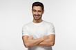 © Damir Khabirov - Handsome man with crossed arms smiling and winking, looking at camera isolated on gray background