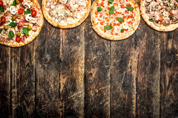 variety of pizzas. On wooden background