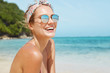 © WHstudio Leushin N - Close up shot of pleasant looking female wears headband and sunglasses, travels in tropical country, poses against warm peaceful ocean, blue sky and rocky cliff in background. Good relaxation