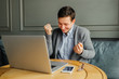 © deineka - Euphoric winner happy man using a laptop in a desk at cafe.