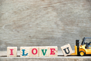 Poster - Toy forklift hold letter block u to complete word I love u on wood background (Concept for Valentine 's day)