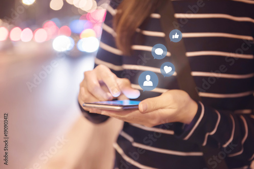 Fotografia Woman hands using mobile smartphone in the street with icon social media and social network